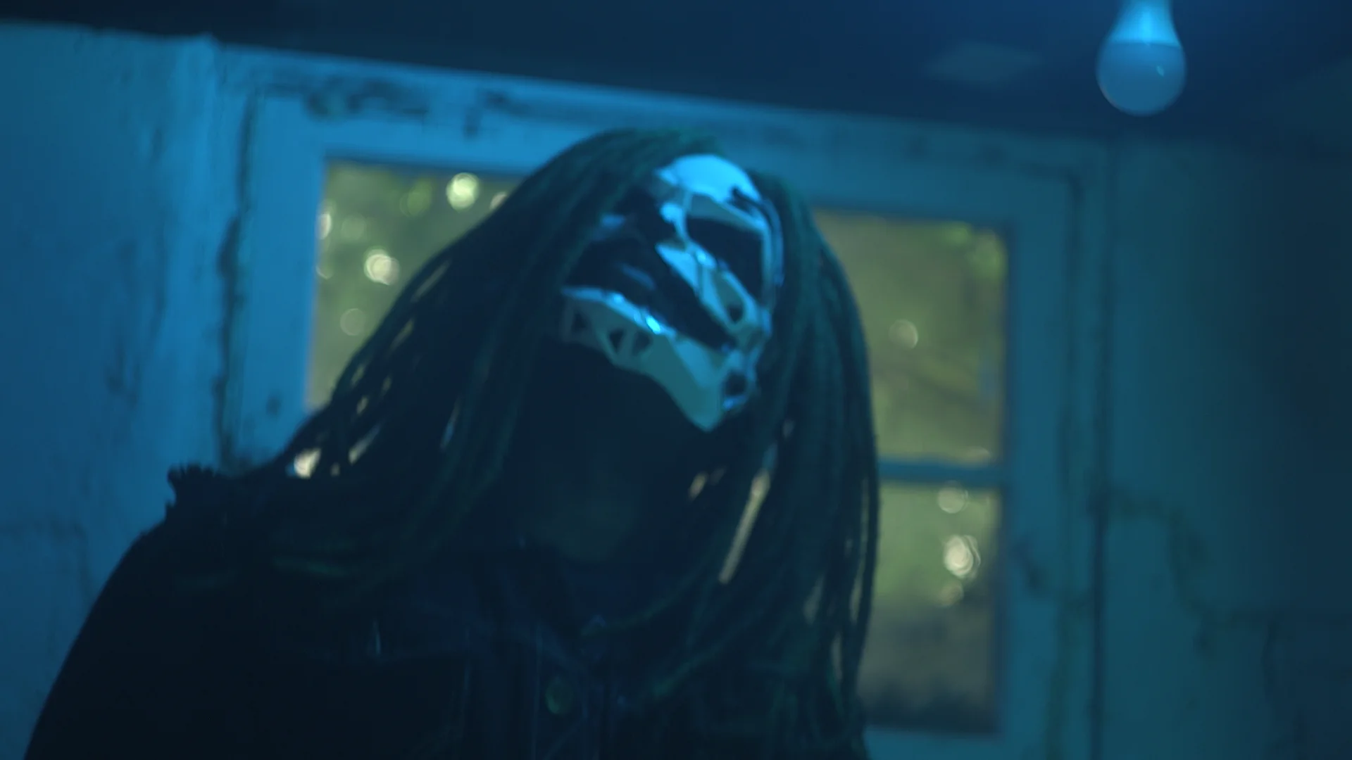 Jai Ghost looking upward beneath a blue basement light